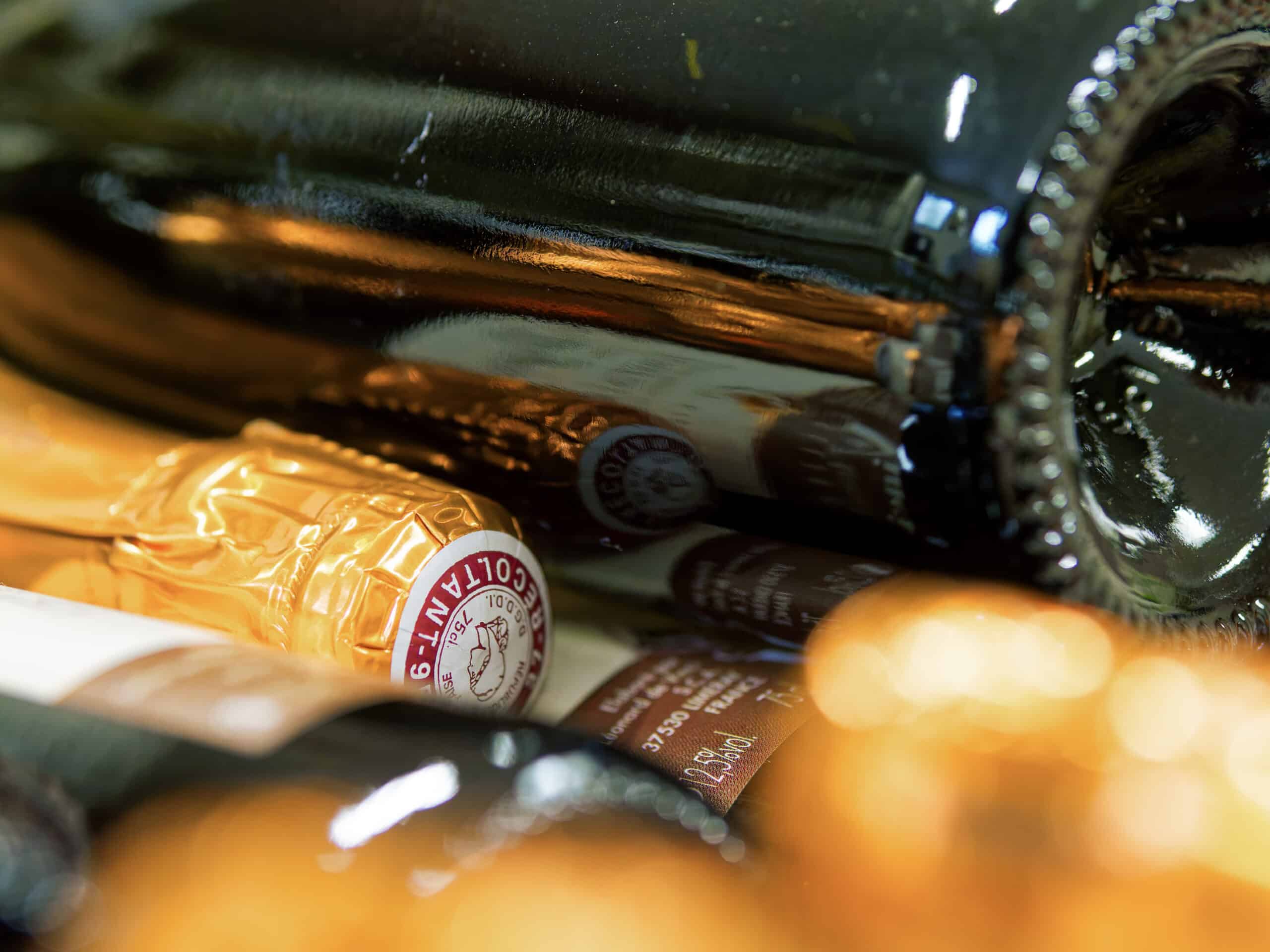 Bouteilles de Champagne Récoltant : Gros Plan de Cave Gros plan sur des bouteilles de champagne avec étiquettes Récoltant et 12,5% vol, capsules dorées et reflets élégants.