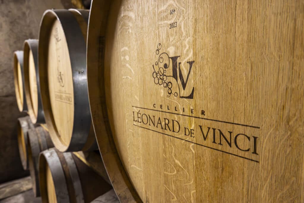 Barriques de vin Cellier Léonard de Vinci - Millésime 2023 Tonneaux de vin en chêne du Cellier Léonard de Vinci gravés du logo LV et millésime 2023 dans un chai.